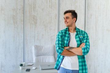 A young guy doing business work in his home office during the day while talking on phone using laptop and his mobile phone	
