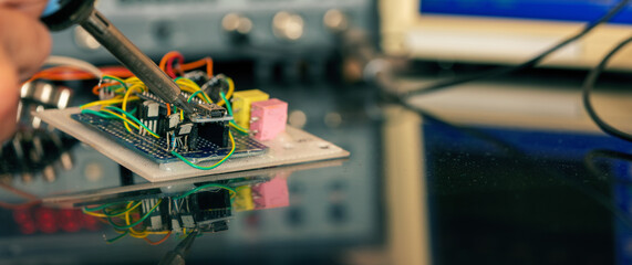 Manufacturing and setting up an electronic device in the laboratory. Soldering iron and electronic...