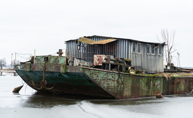Fototapeta na wymiar Zegrze, Poland - January 26, 2022: Old rusty barge on the frozen water. Water transport.