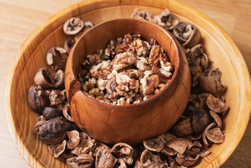 Delicious and healthy peeled walnuts on a wooden authentic plate, there are walnut shells nearby