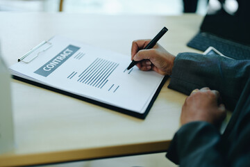 A businesswoman or a female business owner signs important documents to borrow money for investment in real estate or homes with the bank