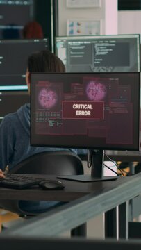 Vertical video: Diverse team of coders having server hacked and system crash, running critical error message flashing on screen with multiple monitos. Displaying hacking alert warning, cyber crime.