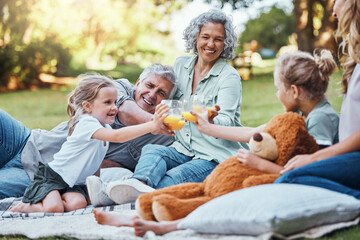 Family, cheers with juice and a picnic in park on happy summer weekend with smile. Grandma, grandpa...