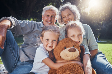 Family, children and teddy bear with a girl, grandparents and sister on the grass in a nature park...