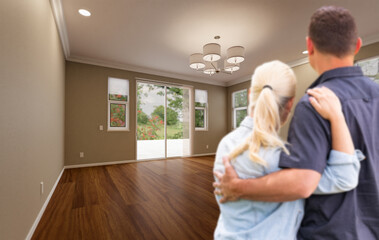 Young Adult Couple Looking At Empty Room of New House.
