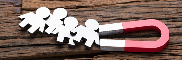 Magnet Attracting People On Wood