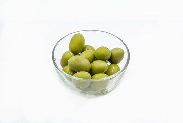 Whole green olives closeup in a clear glass bowl