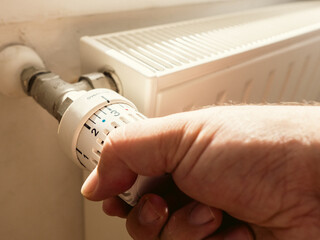 Main d'homme baissant le thermostat de son chauffage radiateur - Personne qui règle la...