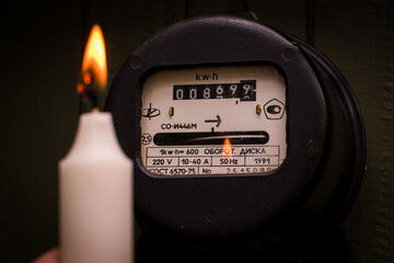 Checking old retro Russian electric meter with candle light. Energy crisis and power outage. High...