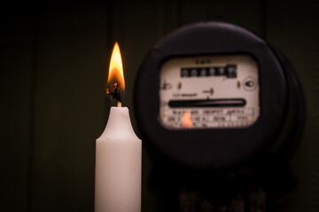 Checking old retro Russian electric meter with candle light. Selective focus on fire. Energy crisis...
