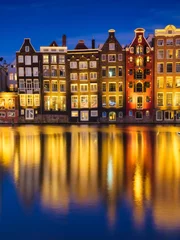 Fototapeten Damrak, Amsterdam, Netherlands. View of houses during sunset. The famous Dutch canals. A cityscape in the evening. Travel photography. © biletskiyevgeniy.com