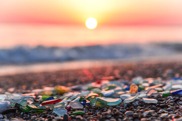Colored sea glass with beach pebbles and shells in the mediterranean coast and in the background...