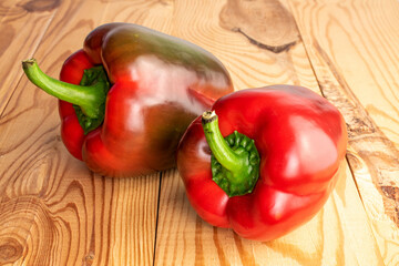 Two red organic, bell peppers, close-up, on a wooden table.