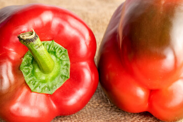 Two juicy ripe bell peppers, close-up, on sacking.