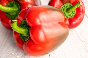 Three red organic, bell peppers, close-up, on a wooden table.