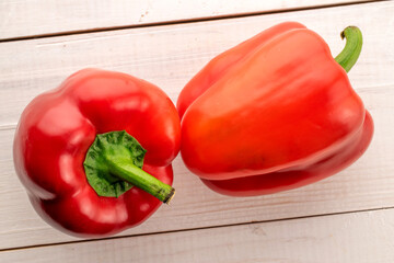 Two juicy red sweet peppers on a wooden table, close-up, top view.