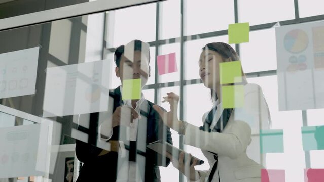 Asian business meeting in front of acrylic glass board with color post it in office work