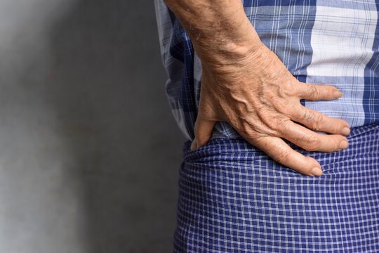 Asian man suffering from left sided low back and loin pain. It can be caused by mechanical or pathological process.