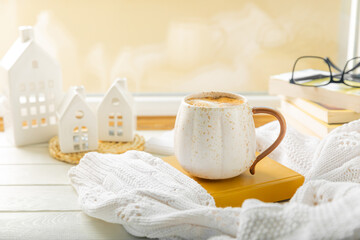 Autumn composition, a hot cup of coffee, candles, candlesticks, a miniature house and a warm sweater on a wooden table.Seasonal, morning hot coffee. Relaxing and still life concept.Cozy interior decor