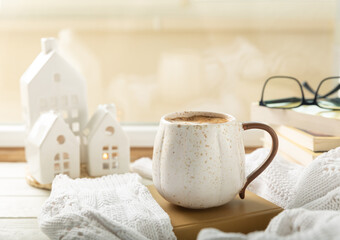 Fototapeta na wymiar Autumn composition, a hot cup of coffee, candles, candlesticks, a miniature house and a warm sweater on a wooden table.Seasonal, morning hot coffee. Relaxing and still life concept.Cozy interior decor