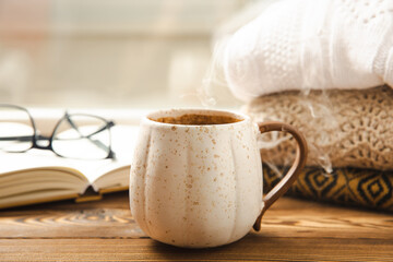 Autumn. Autumn composition, a hot cup of coffee and a warm sweater on a wooden textured table. Seasonal, morning hot coffee.Relaxing and still life concept. Cozy interior