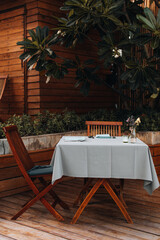 Tableclothed table and wooden chairs in a summer outdoor restaurant