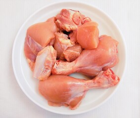 Raw fresh chicken meat white-meat murghi ka gosht boti raw-frango raw-poulet, food uncooked poultry-meat raw-pollo hen-meat cut pieces on a plate fillets and drumstick bird-meat closeup image photo 