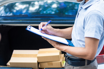 A courier is delivering a parcel box to a customer at the door of a private car.