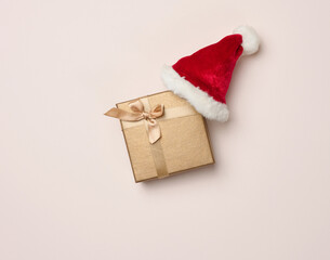 Square box and red santa hat on a beige background. Christmas decor, top view