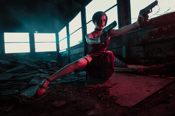 young beautiful girl in an evening red dress with a gun