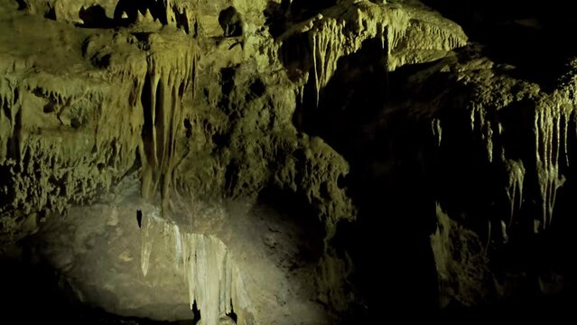 Beautiful cave with stalactites underground cavern in magic light, tilt view 4k
