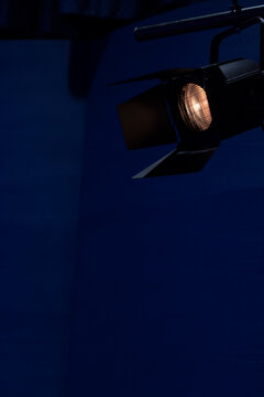 A stage light with barn doors eminating a warm light in a blue ambiance