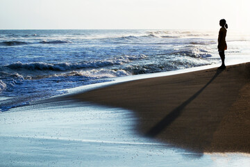 A silhouette of a lonely woman on the beach at sunset