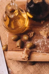 Foto op Canvas Vertical shot of olive oil vinegar and green olives on a cutting board © Nacho Ramirez/Wirestock Creators