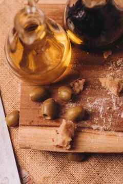 Vertical shot of olive oil vinegar and green olives on a cutting board