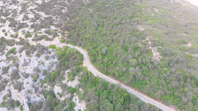 Kurviger Bergweg in Italien auf der Insel Sardinien mit mediterraner Landschaft und Bergen im Hintergrund