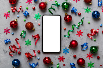Christmas online shopping from home phone with blank white display top view. smart mobile with copy space on colored background with Christmas decorations balls,. Winter holidays sales background
