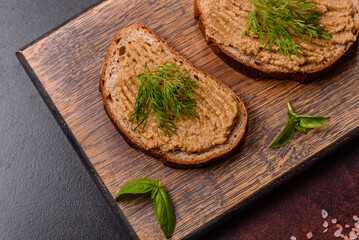 Homemade meat snack liver pate with toast on a dark concrete background