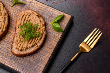 Homemade meat snack liver pate with toast on a dark concrete background