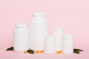 Omega-3 capsules lie in white bottle on a table with green leaves background. Fish oil tablets. Biologically active additives. omega 6, omega 9, vitamin A, E, D, vitamin D3 top view with copy space