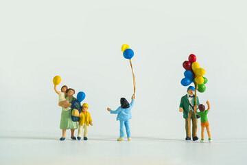 Family with cheerful children holding colorful balloons at a balloon seller isolated on white...