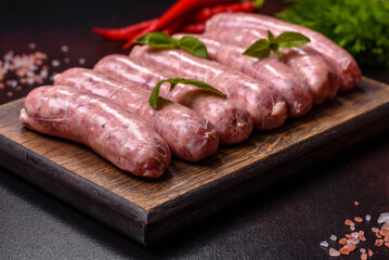 Raw sausages with ingredients on a cutting board on a dark concrete background with copy space