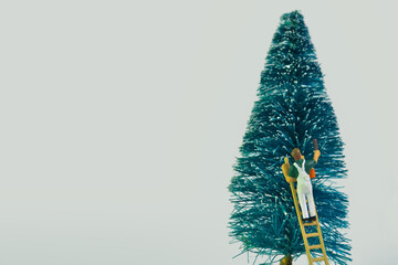 A painter standing on a ladder paints a fir tree isolated on white background