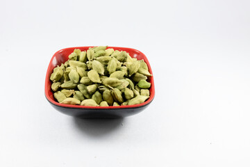 Green cardamom or cardamon or cardamum or green elaichi in a bowl isolated on white background. Top view. Close up
