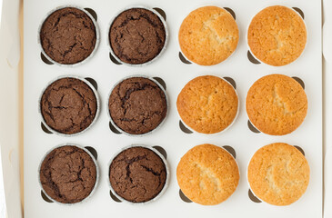 Set of brown chocolate and white vanilla cupcakesin the white gift box. Flat lay