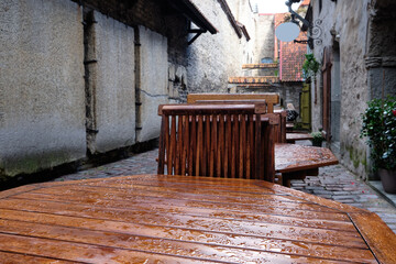 Catherine Lane in Tallinn, Estonia, on a rainy day. Wet tables and chairs of outdoor cafe. Ancient...