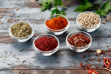 Various spices in bowls on grey table. Paprika, turmeric, red pepper, cumin, coriander. Powdered spices
