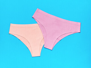 Beige and pink women's panties on a blue background. The concept of women's underwear.
