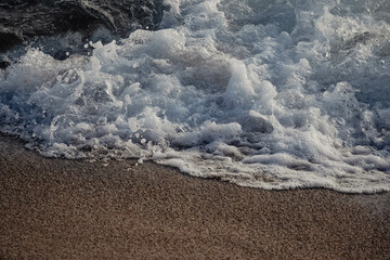 Paisaje de la orilla de una playa con olas y espuma

