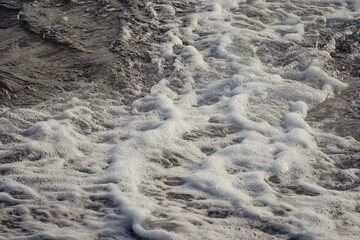 Paisaje de la orilla de una playa con olas y espuma
